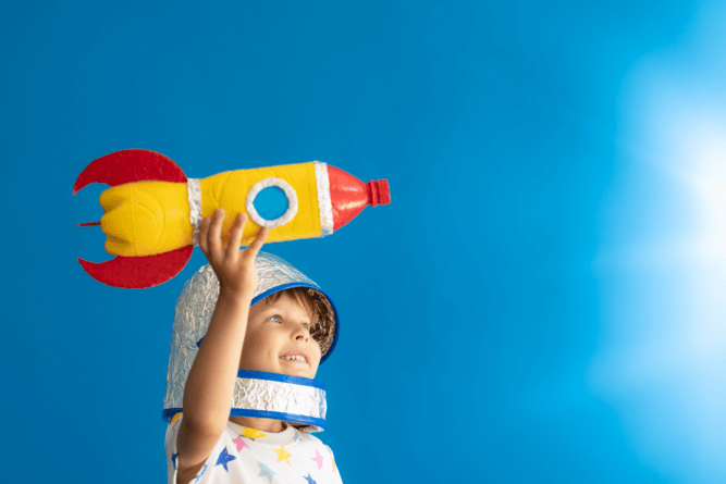 Kid flying a homemade rocket under blue sky